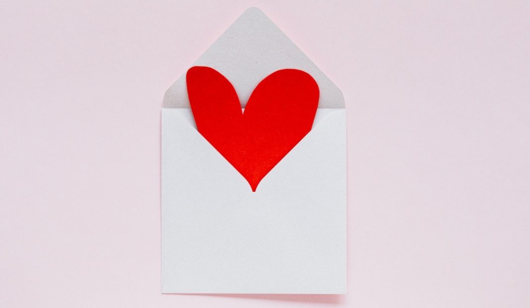 A paper heart is part way out of an envelope.