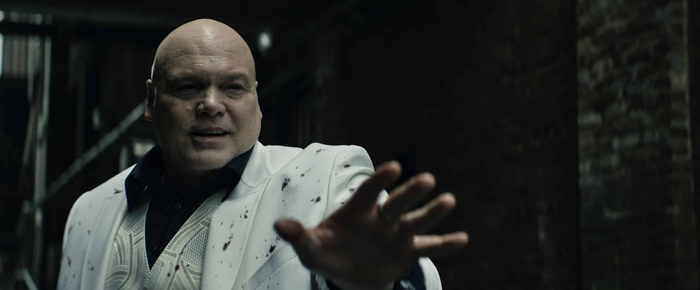 Fisk, a large, bald white male character portrayed by Vincent D'Onofrio, wears a white suit and holds out his hand in a plea.