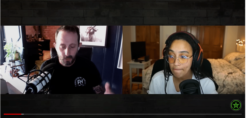 Screenshot of a video of Geoff Ramsey, a white man with short brown hair, mustache, and beard, and Fiona Nova, a black woman with long braided black hair, seated in front of microphones at home.