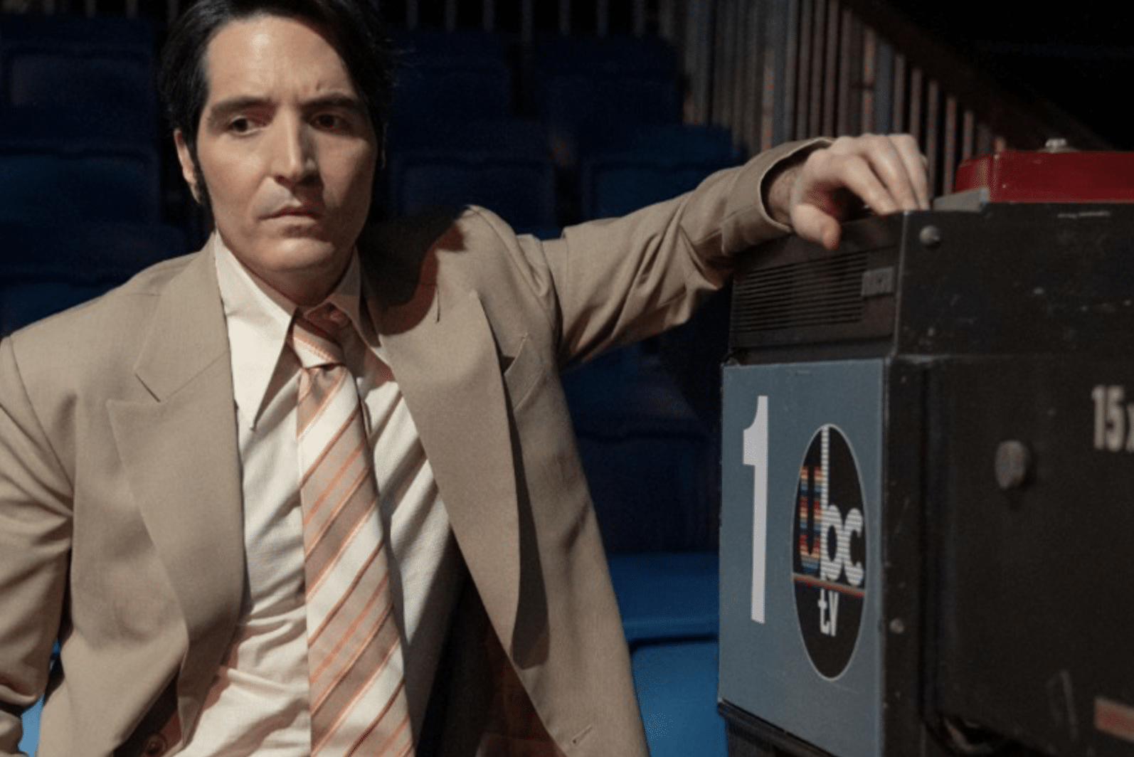 Jack Delroy (played by David Dastmalchian) leans on a studio camera pondering his life choices.