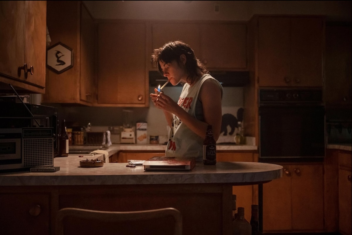 Kristen Stewart smokes in a kitchen in Love Lies Bleeding.