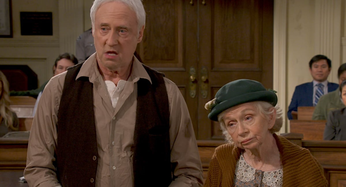 An elderly couple stands together in court