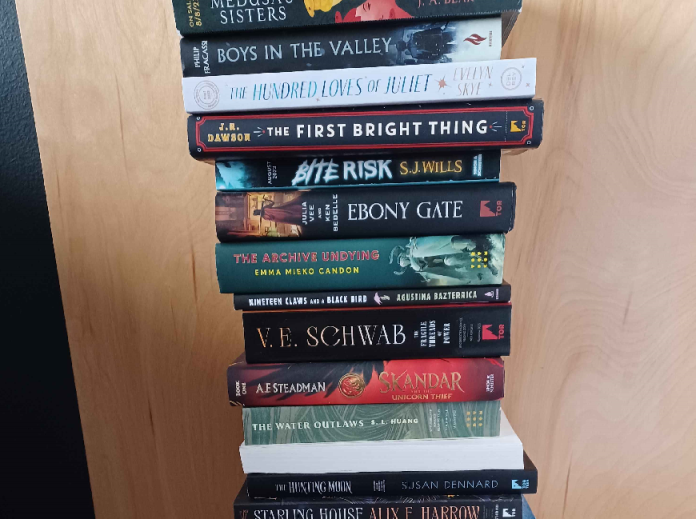 bookedit Several books in a stack against a brown wooden door backdrop