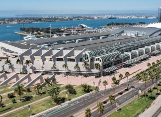 SDCC ’24: SDCC clears Hall H for the very first time An aerial view of the San Diego Convention Center, a large white brutalist structure with glass by the harbor.