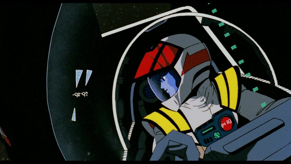 Macross: Do You Remember Love? Hikaru sits in cockpit of Valkyrie, looking out towards the right.