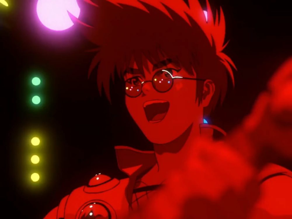 Macross 7. Basara the rock star plays guitar while he smiles at the camera. He is wearing glasses and a vest. A line of pink, green and blue lights is to his right.