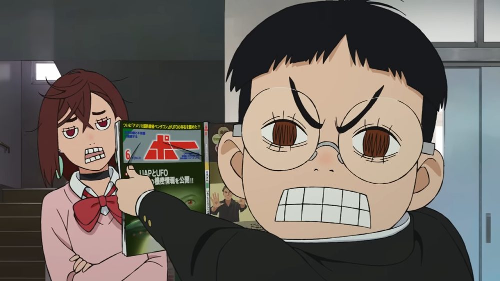 teenage boy with bowl cut shows magazine to skeptical teenage girl wearing a pink jacket