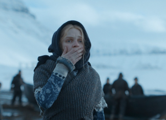 Horror Beat: THE DAMNED only damns itself Odessa Young standing in front of men on a bleak white shoreline in The Damned