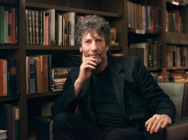 Monomythic: On Neil Gaiman and how to get over your idols: a question, not a statement Neil Gaiman is sitting on a chair with rows of books behind him
