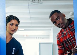 DOCTOR WHO spins its rotors in season premiere “The Robot Revolution” The Doctor (Ncuti Gatwa) and the Nurse, Belinda Chandra (Varada Sethu) peak behind a pair of blue curtains.