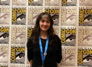 Interview: Anna Meyer talks SAINT CATHERINE, trauma, and why religious stories are timely Anna Meyer in front of SDCC backdrop