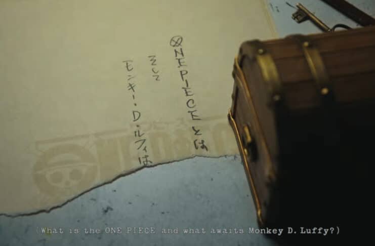 Close up of the treasure chest containing the awnser of what is the One Piece with one half of the answer on display, written on a sheet of paper beneath the chest.