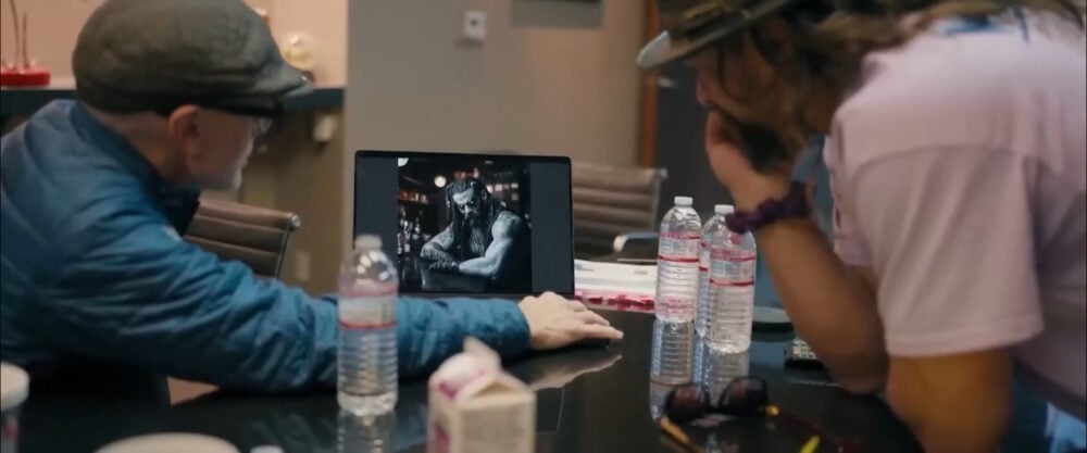 Craig Gillespie and Jason Momoa discussing a Lobo design (with a visible ear) on a laptop