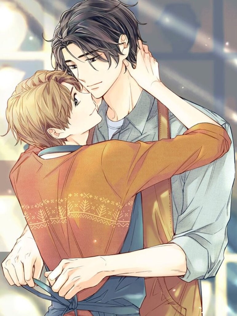 An image from Unintentional Love Story. A taller man with black hair ties the blue apron of a shorter man with brown hair.