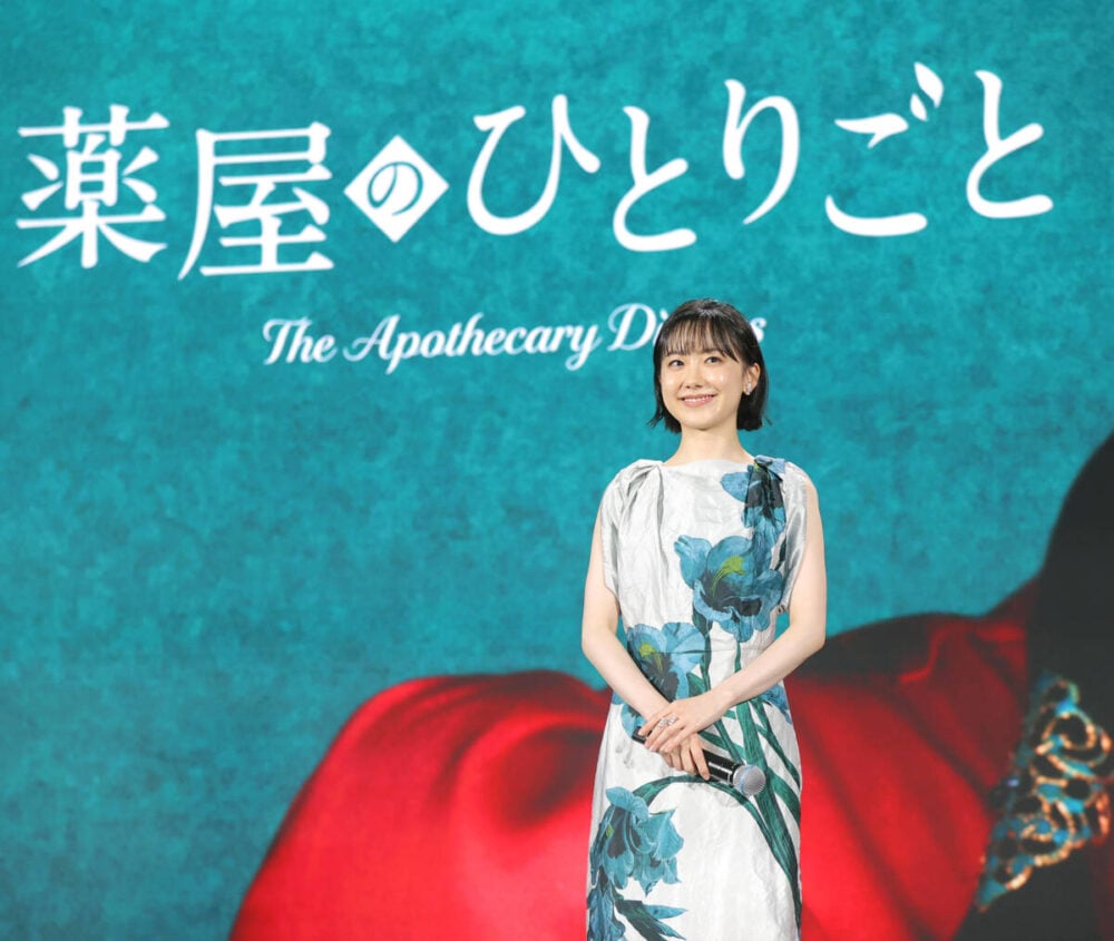 actress Mana Ashida who will be starring as Maomao, is standing in front of the teaser visual for The Apothecary Diaries live-action adaptation.