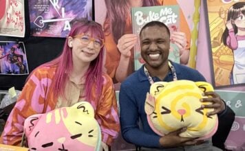 NYCC ‘26: Kim-Joy discusses QUIET graphic novel and bringing baking and mental health into graphic novels The Beat reporter Aaron Halls and Kim-Joy seated at artist alley at NYCC '26 to discuss Quiet smiling and holding plushies.