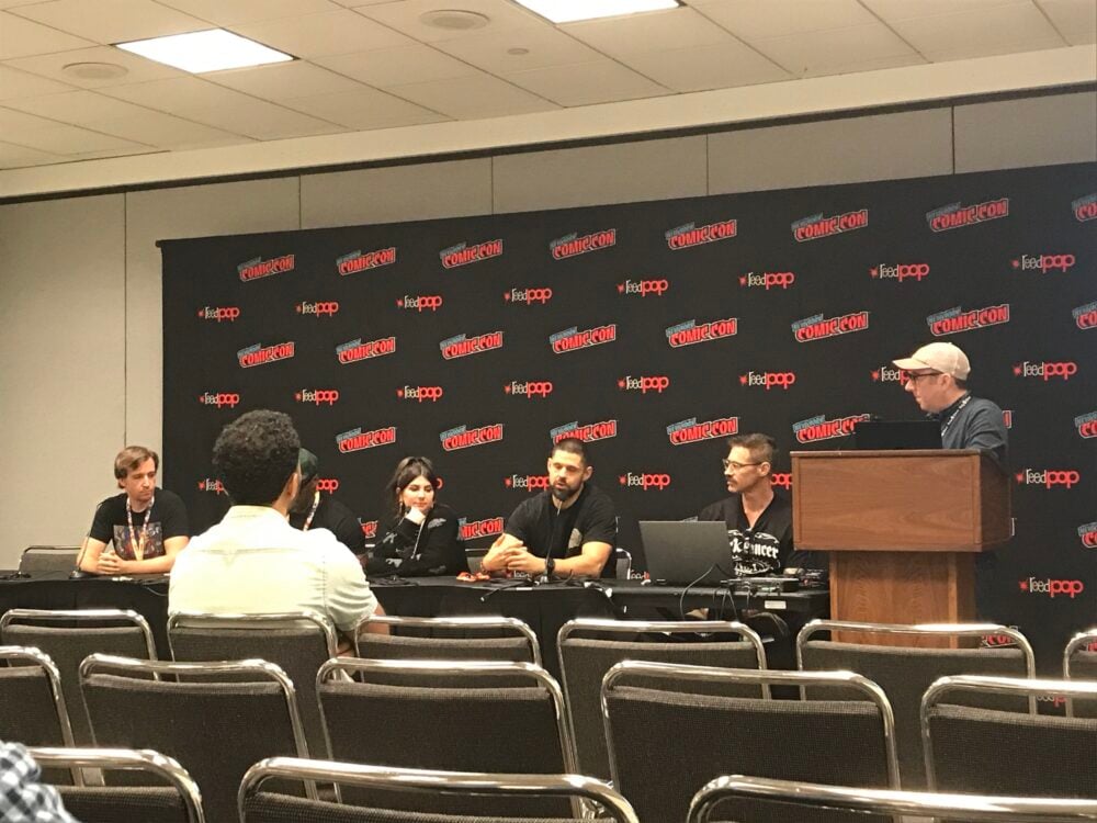 A view of the Rocketship Entertainment panel, the panelists are sitting in front of a NYCC and reedpop banner with one person visibly seated in the front row, but other nearby seats remain empty.